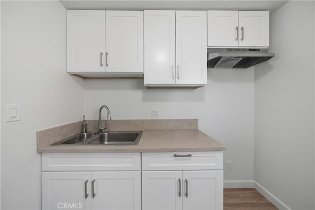 407 W 107th St, Los Angeles, CA 90003 - kitchen featuring under cabinet range hood, a sink, baseboards, white cabinetry, and wood finished floors