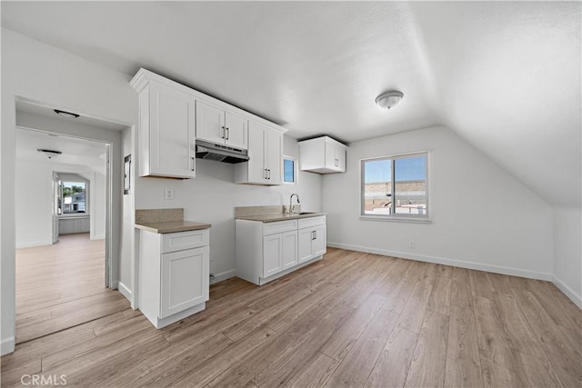 407 W 107th St, Los Angeles, CA 90003 - kitchen with under cabinet range hood, light wood-style floors, white cabinets, a sink, and lofted ceiling