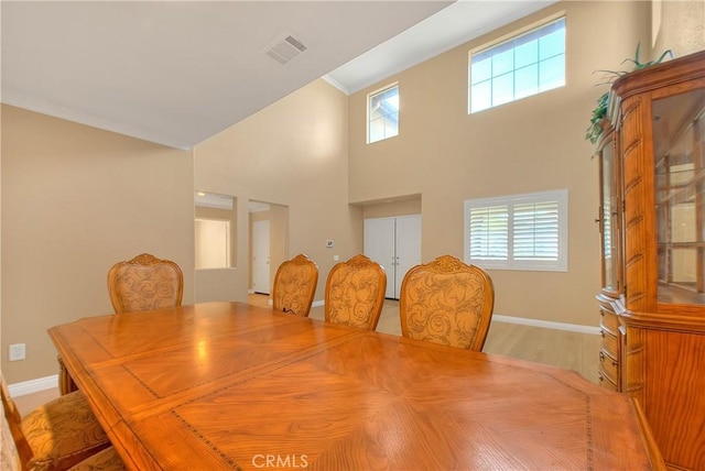 12415 Brianwood Dr, Riverside, CA 92503 - dining space with healthy amount of natural light, baseboards, a towering ceiling, ornamental molding, and light wood-style floors