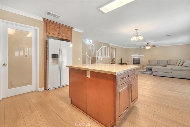 12415 Brianwood Dr, Riverside, CA 92503 - kitchen with white refrigerator with ice dispenser, light wood finished floors, a chandelier, ornamental molding, and brown cabinetry