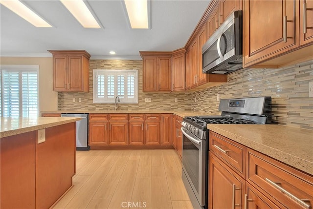 12415 Brianwood Dr, Riverside, CA 92503 - kitchen featuring stainless steel appliances, light wood-style flooring, brown cabinets, backsplash, and crown molding