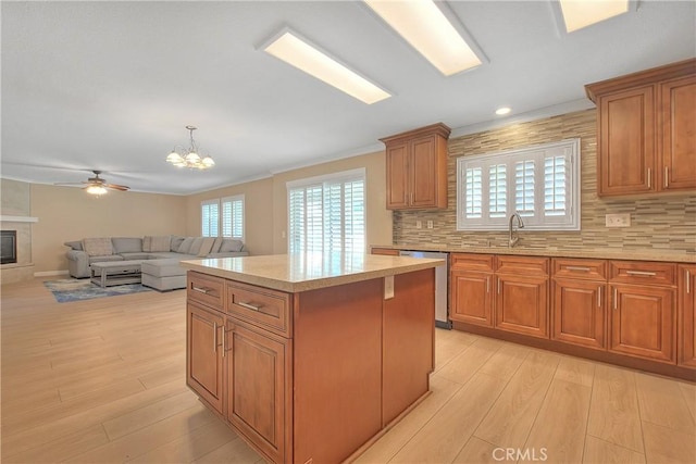 12415 Brianwood Dr, Riverside, CA 92503 - kitchen with stainless steel dishwasher, light wood-style flooring, a kitchen island, brown cabinets, and tasteful backsplash