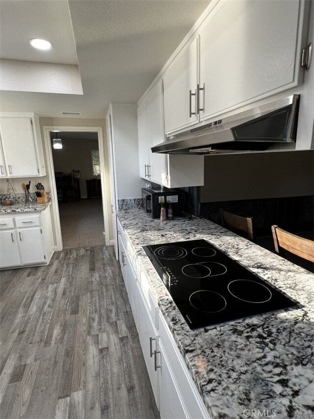 108 Limestone Rd, Claremont, CA 91711 - kitchen with under cabinet range hood, black electric cooktop, white cabinets, wood finished floors, and light stone countertops
