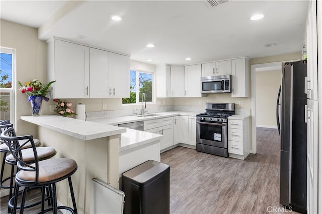 4950 N Treanor Ave, Covina, CA 91724 - kitchen with appliances with stainless steel finishes, a sink, a peninsula, white cabinets, and recessed lighting