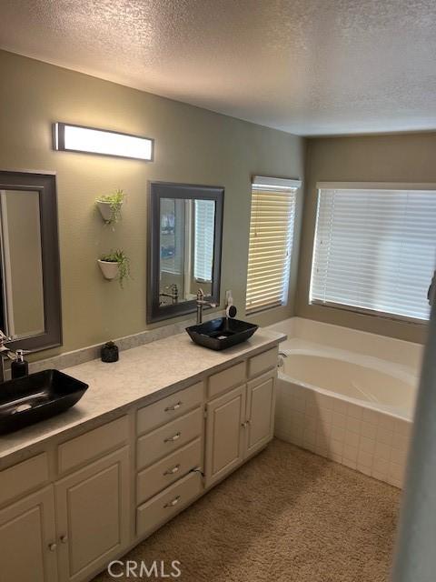 3762 Segovia Dr, Perris, CA 92571 - bathroom with a textured ceiling, double vanity, and a bath