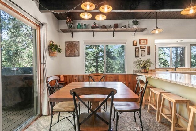 1213 Jungfrau Dr, Crestline, CA 92325 - dining area featuring a wooden ceiling with exposed beams, a wainscoted wall, light carpet, and wood walls