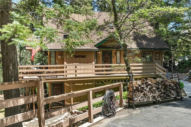 1213 Jungfrau Dr, Crestline, CA 92325 - rustic home with a shingled roof, board and batten siding, and a deck