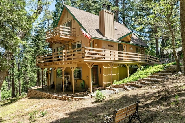 1213 Jungfrau Dr, Crestline, CA 92325 - back of property with a shingled roof, a chimney, a deck, and a balcony