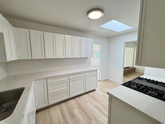 1335 S Hickory St, Anaheim, CA 92805 - kitchen with a skylight, light wood-style flooring, white cabinetry, and a sink