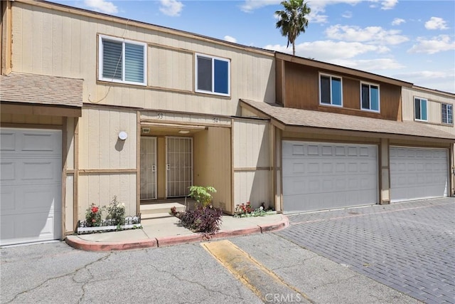 12828 Ramona Blvd Unit 54, Baldwin Park, CA 91706 - view of property featuring roof with shingles, an attached garage, and decorative driveway