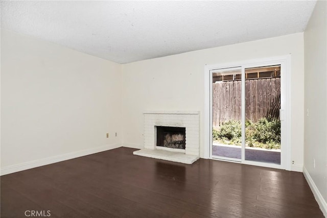 12828 Ramona Blvd Unit 54, Baldwin Park, CA 91706 - unfurnished living room featuring dark wood finished floors, a brick fireplace, baseboards, and a textured ceiling