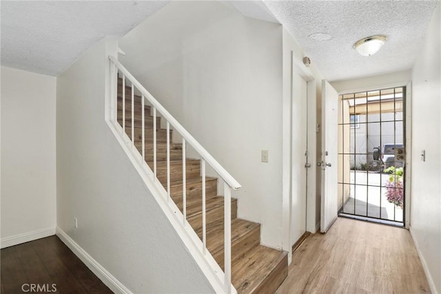 12828 Ramona Blvd Unit 54, Baldwin Park, CA 91706 - foyer entrance featuring wood finished floors, a textured ceiling, baseboards, and stairway