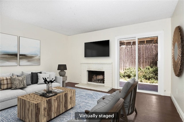 12828 Ramona Blvd Unit 54, Baldwin Park, CA 91706 - living area with baseboards, dark wood-style flooring, a brick fireplace, and a textured ceiling