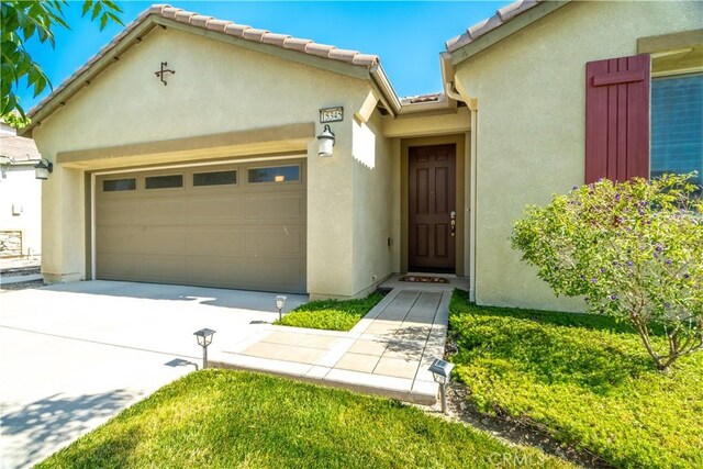 15345 Chive Ln, Fontana, CA 92336 - view of front of home with a garage, stucco siding, concrete driveway, and a tile roof