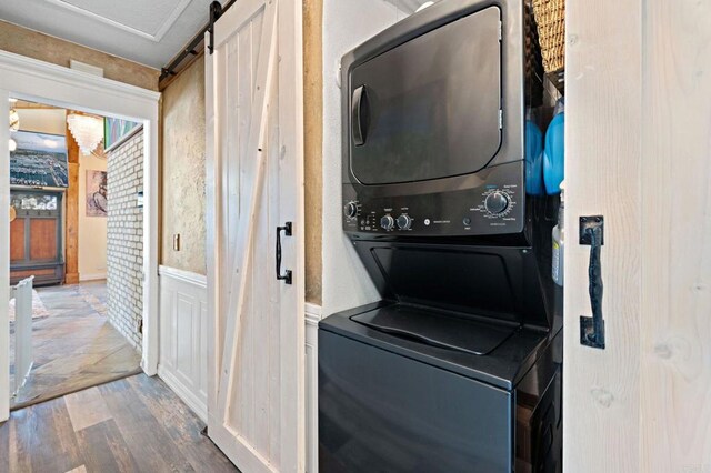 2042 Pheasant Run, Fallbrook, CA 92028 - washroom featuring stacked washer / dryer, wood finished floors, a barn door, and a wainscoted wall