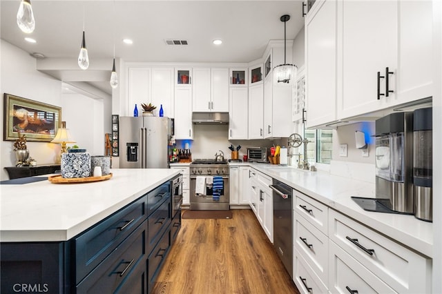 7256 Plumrose St, Fontana, CA 92336 - kitchen with stainless steel appliances, under cabinet range hood, white cabinets, decorative light fixtures, and wood finished floors