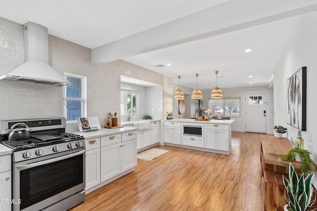 1015 Nolden St, Highland Park, CA 90042 - kitchen featuring stainless steel appliances, wall chimney range hood, decorative backsplash, light wood finished floors, and light countertops