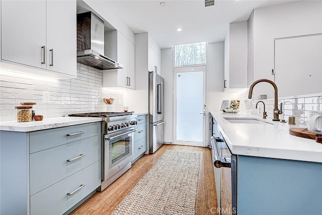 1436 N Detroit St Unit 2, Los Angeles, CA 90046 - kitchen with high end appliances, wall chimney range hood, a sink, backsplash, and light wood-style flooring