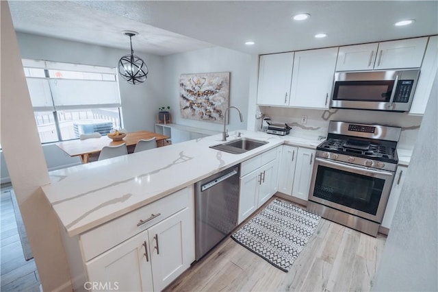25598 Mont Pointe Unit 4E, Lake Forest, CA 92630 - kitchen featuring appliances with stainless steel finishes, a sink, a peninsula, light stone countertops, and a chandelier