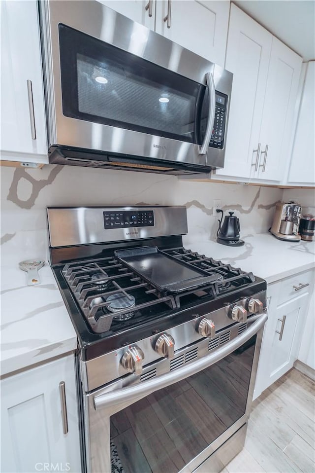 25598 Mont Pointe Unit 4E, Lake Forest, CA 92630 - kitchen view of appliances with stainless steel finishes, white cabinetry, light wood-type flooring, and light stone counters