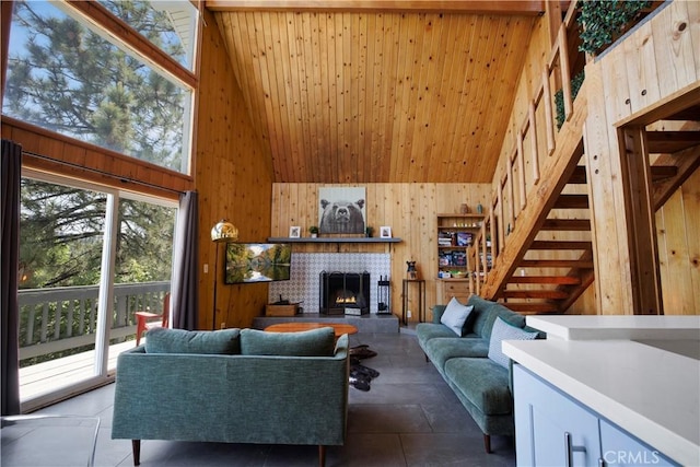 26503 Amador Ln, Lake Arrowhead, CA 92352 - living area with high vaulted ceiling, wooden walls, a warm lit fireplace, stairs, and wooden ceiling