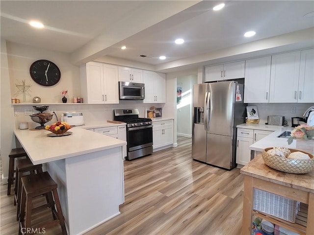 6678 Wrangler Rd, Chino Hills, CA 91709 - kitchen with appliances with stainless steel finishes, a peninsula, light wood-style flooring, light countertops, and white cabinets