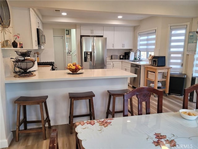 6678 Wrangler Rd, Chino Hills, CA 91709 - kitchen featuring appliances with stainless steel finishes, a peninsula, light wood finished floors, light countertops, and white cabinetry
