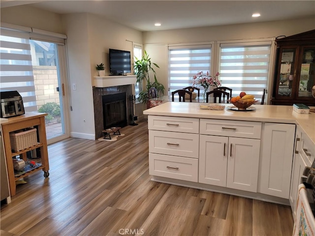 6678 Wrangler Rd, Chino Hills, CA 91709 - kitchen with a fireplace with flush hearth, light wood-type flooring, white cabinetry, healthy amount of natural light, and recessed lighting