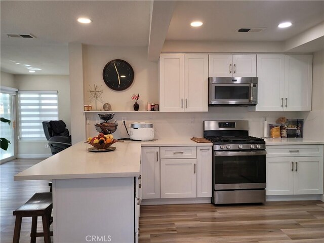 6678 Wrangler Rd, Chino Hills, CA 91709 - kitchen with appliances with stainless steel finishes, a peninsula, white cabinets, light wood-style flooring, and recessed lighting