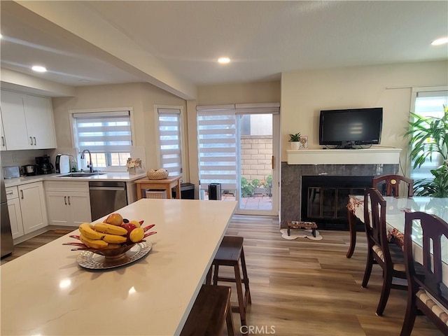 6678 Wrangler Rd, Chino Hills, CA 91709 - kitchen featuring stainless steel dishwasher, white cabinets, a premium fireplace, a kitchen breakfast bar, and wood finished floors
