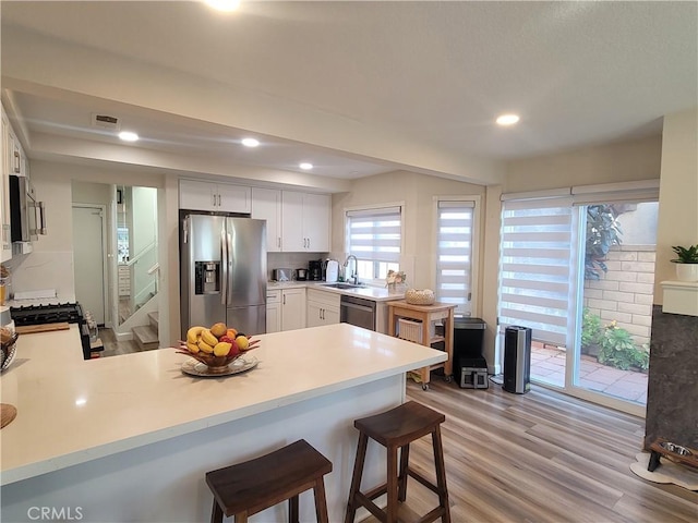 6678 Wrangler Rd, Chino Hills, CA 91709 - kitchen featuring appliances with stainless steel finishes, a peninsula, a kitchen bar, light countertops, and recessed lighting
