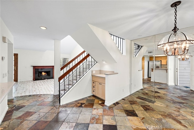 601 San Nicholas Ct Unit 601, Laguna Beach, CA 92651 - staircase with stone tile flooring, baseboards, a chandelier, a lit fireplace, and recessed lighting