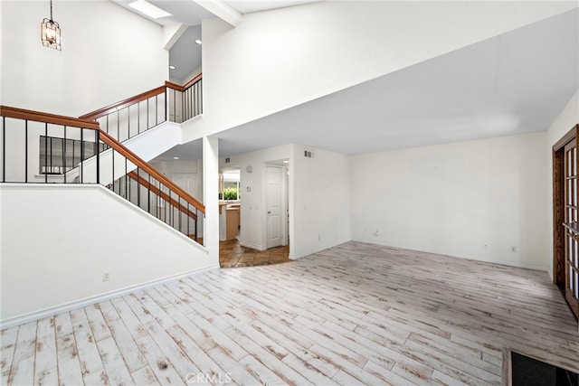 601 San Nicholas Ct Unit 601, Laguna Beach, CA 92651 - unfurnished living room with wood finished floors, stairway, a high ceiling, and baseboards