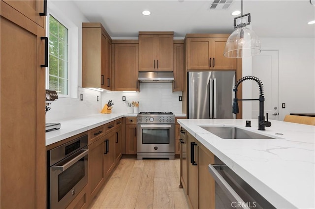 1146 E Cove Pl, Encinitas, CA 92024 - kitchen featuring stainless steel appliances, under cabinet range hood, a sink, light wood-style floors, and brown cabinetry