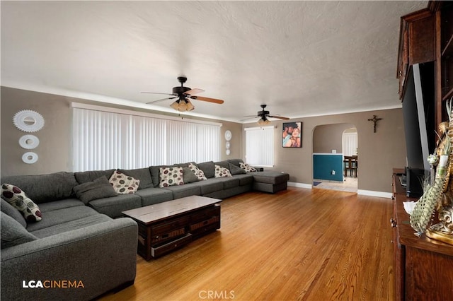 13271 Garzoli Ave, Mcfarland, CA 93250 - living area with arched walkways, a ceiling fan, light wood finished floors, and baseboards