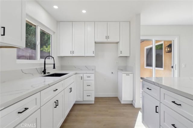 4708 Sunrise Rdg, Oceanside, CA 92056 - kitchen with a sink, white cabinets, light stone counters, light wood finished floors, and recessed lighting