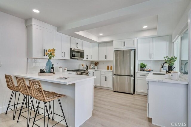 29461 Via Valverde, Laguna Niguel, CA 92677 - kitchen with stainless steel appliances, a peninsula, a raised ceiling, tasteful backsplash, and recessed lighting