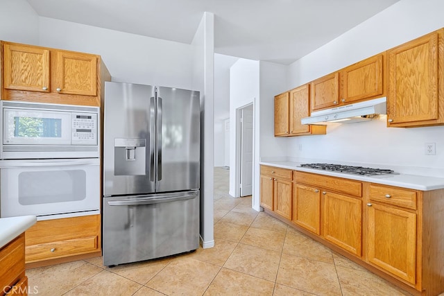 79030 Ladera Dr, La Quinta, CA 92253 - kitchen with white appliances, under cabinet range hood, light countertops, and light tile patterned floors