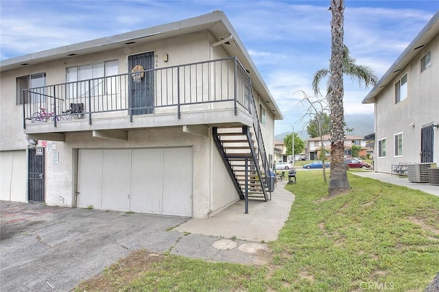 3441 20th St, Highland, CA 92346 - view of side of property with stairway, a lawn, a garage, central AC, and a balcony