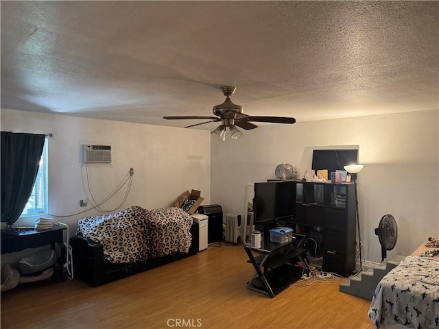 14222 Filmore St, Arleta, CA 91331 - bedroom featuring radiator heating unit, light wood-type flooring, an AC wall unit, a textured ceiling, and ceiling fan