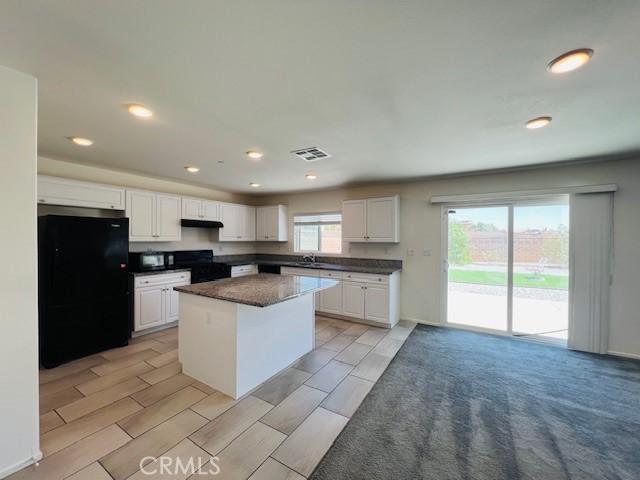 15893 Cordova Rd, Victorville, CA 92394 - kitchen featuring freestanding refrigerator, dark countertops, a kitchen island, white cabinetry, and recessed lighting