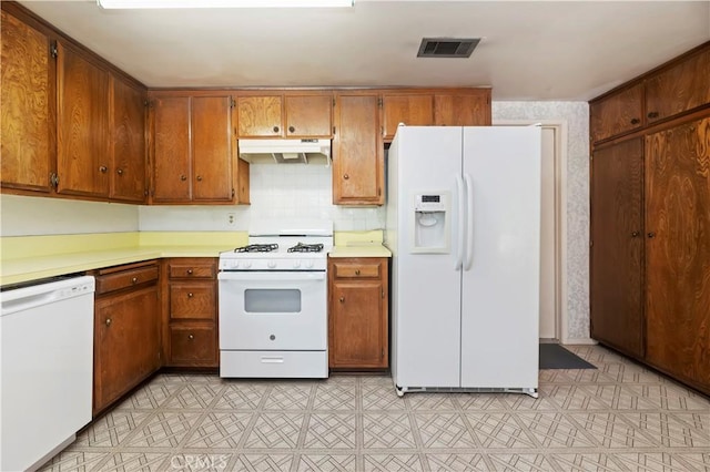 42769 Tierra Robles Pl, Temecula, CA 92592 - kitchen with white appliances, under cabinet range hood, light countertops, and brown cabinets