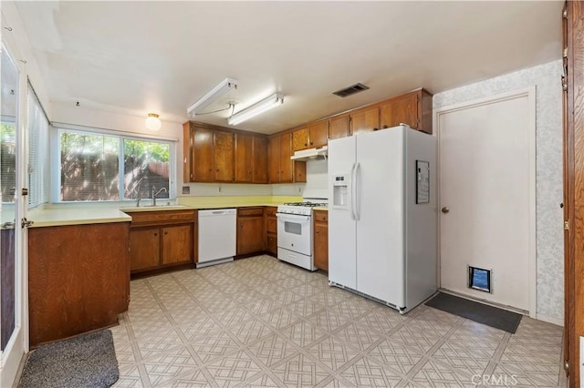 42769 Tierra Robles Pl, Temecula, CA 92592 - kitchen featuring white appliances, brown cabinetry, a sink, light floors, and light countertops