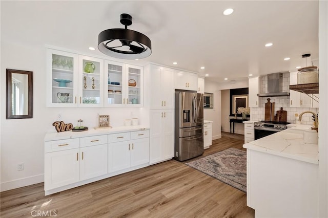 5700 Ravenspur Dr Unit 307, Rancho Palos Verdes, CA 90275 - kitchen featuring appliances with stainless steel finishes, wall chimney range hood, white cabinetry, baseboards, and light wood-style flooring