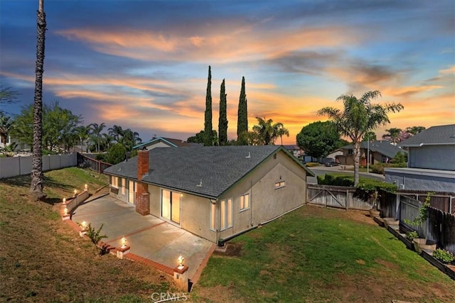 1326 Rosehill Dr, Riverside, CA 92507 - back of house at dusk featuring a fenced backyard, a patio area, driveway, stucco siding, and a gate