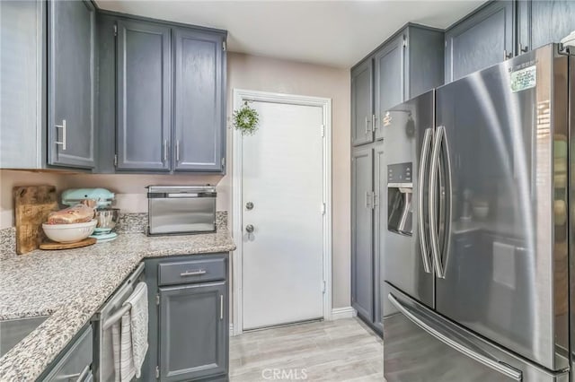 2618 W Loma Vista Dr, Rialto, CA 92377 - kitchen with stainless steel fridge, light wood-style flooring, gray cabinets, and light stone countertops