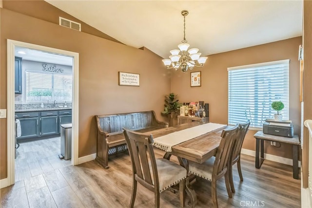 2618 W Loma Vista Dr, Rialto, CA 92377 - dining area featuring a chandelier, light wood-style flooring, lofted ceiling, and baseboards