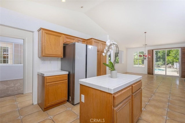 24563 Calle Perla, Murrieta, CA 92562 - kitchen featuring freestanding refrigerator, tile countertops, vaulted ceiling, light tile patterned floors, and a center island