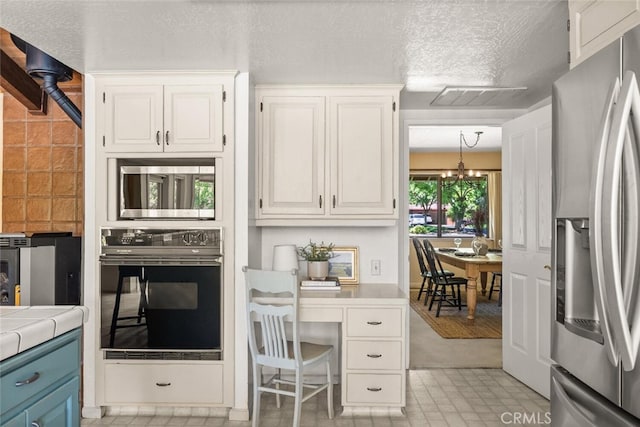 558 Paseo Companeros St, Chico, CA 95928 - kitchen featuring appliances with stainless steel finishes, a chandelier, white cabinetry, tile countertops, and blue cabinets