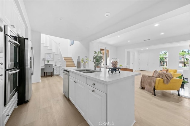 97 Twin Gables, Irvine, CA 92620 - kitchen with a sink, appliances with stainless steel finishes, light wood-type flooring, white cabinets, and a center island with sink